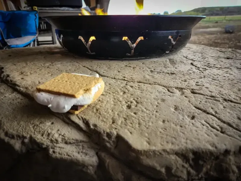 S'more on stone surface near a lit fire pit with decorative cutouts.