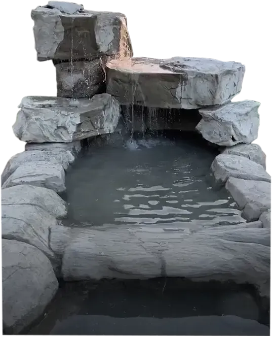 Stone waterfall feature with cascading water into a small pond.