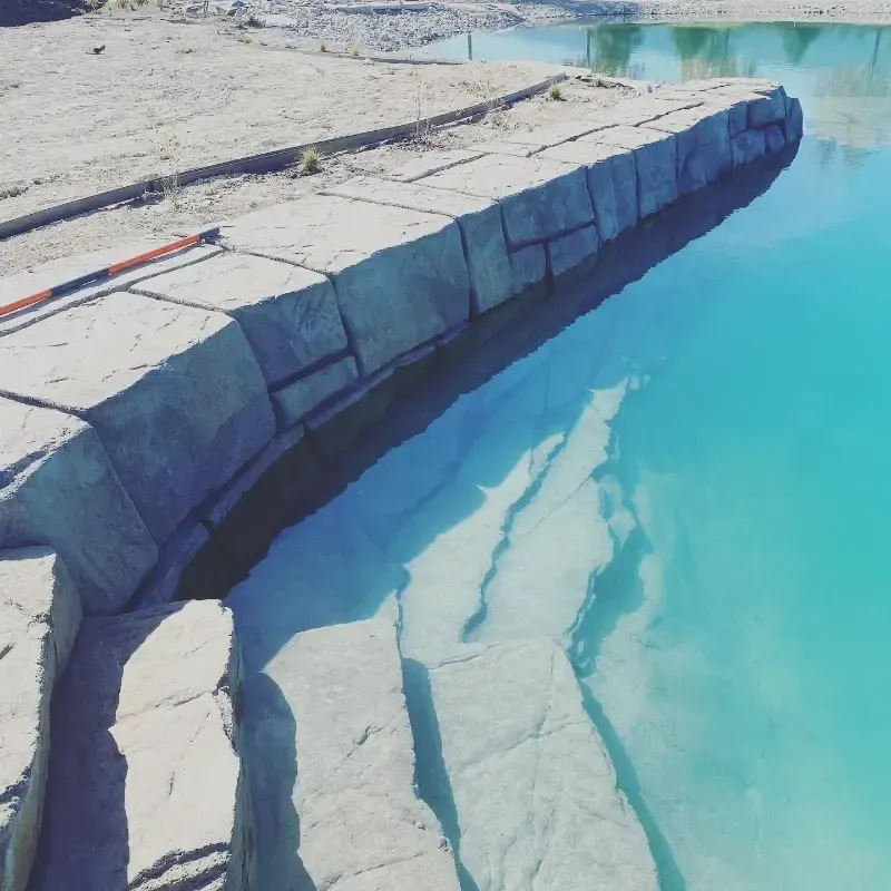 Stone steps leading into clear, turquoise water. Sunny outdoor setting.