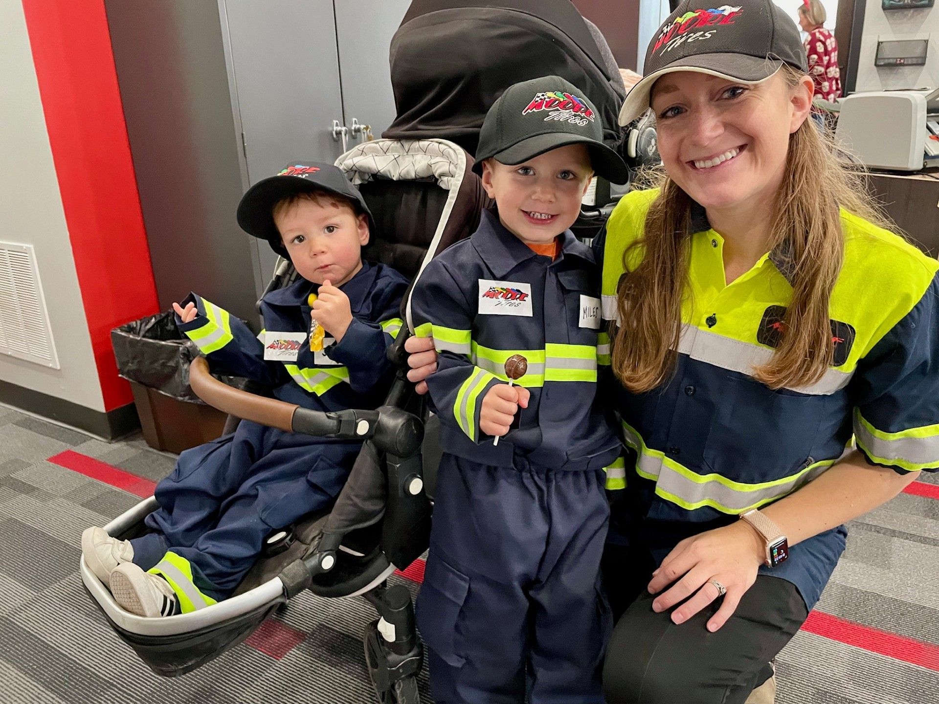 Woman and two children in fire fighter costumes pose for a photo.