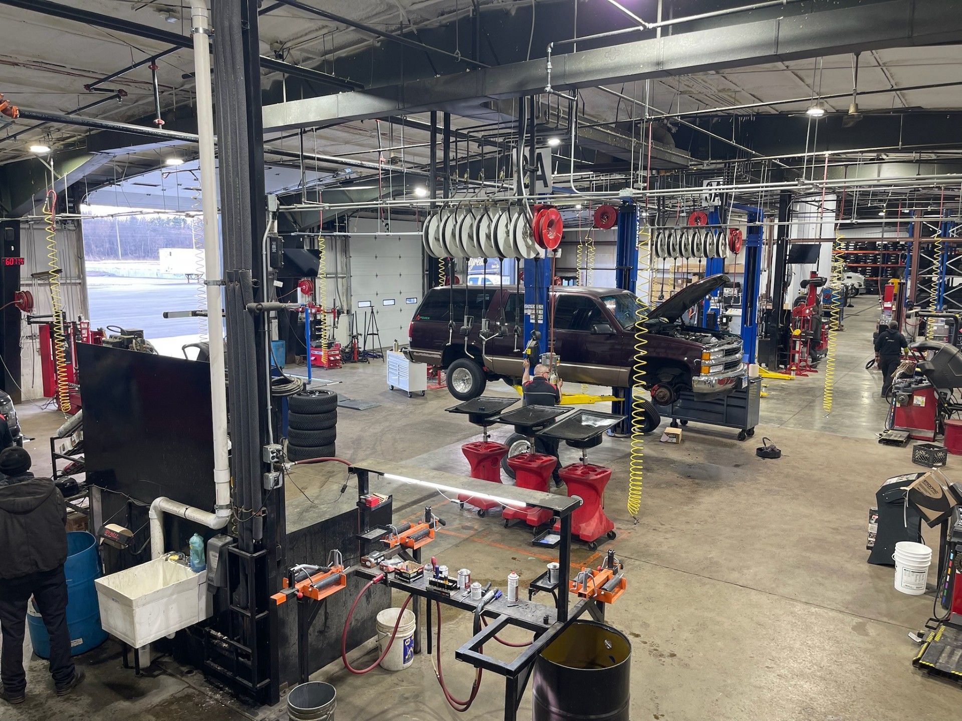 Auto repair shop interior with vehicles on lifts, tools, and a technician working.