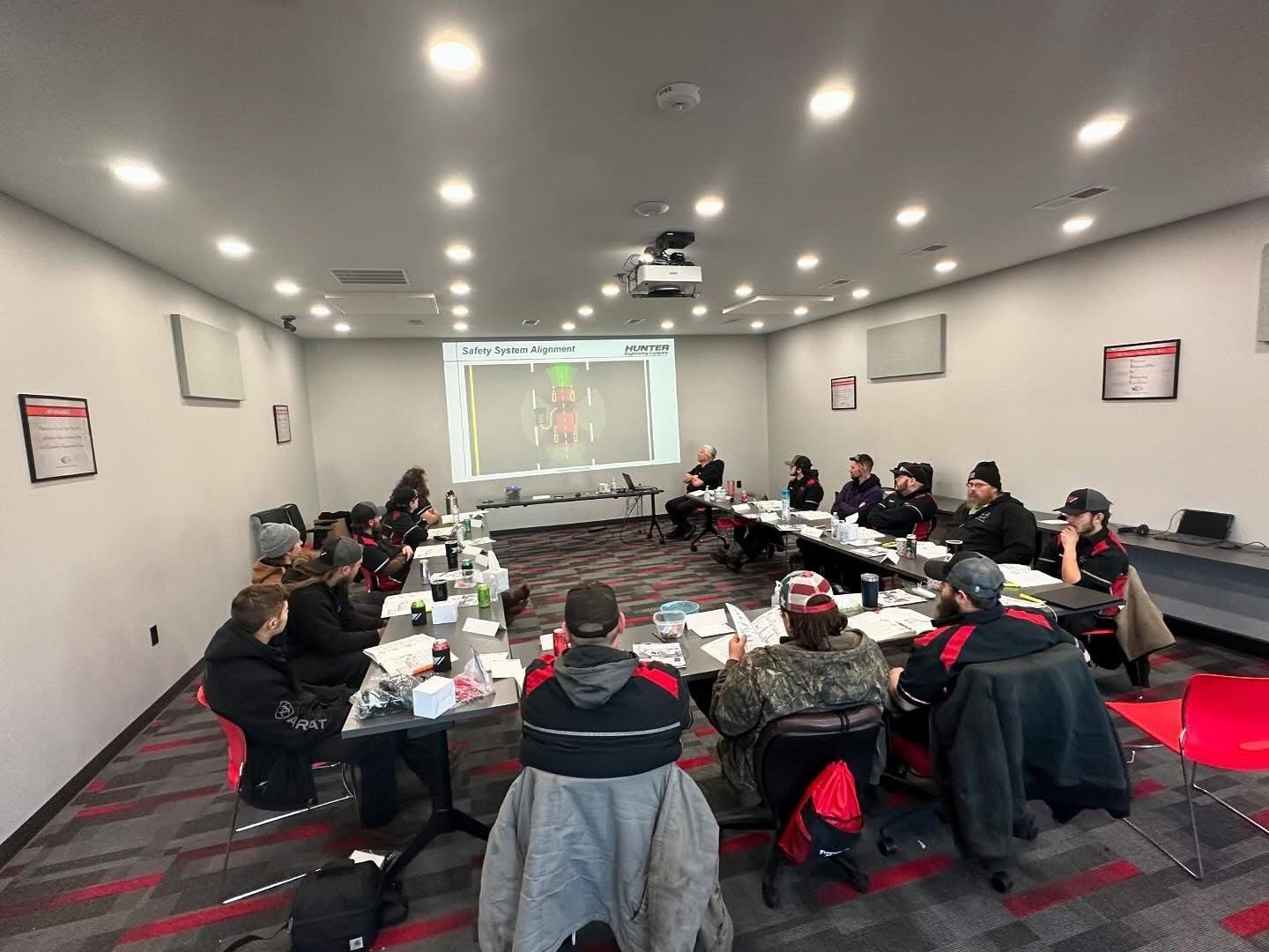 Group of people attending a training session in a meeting room with a projector screen.