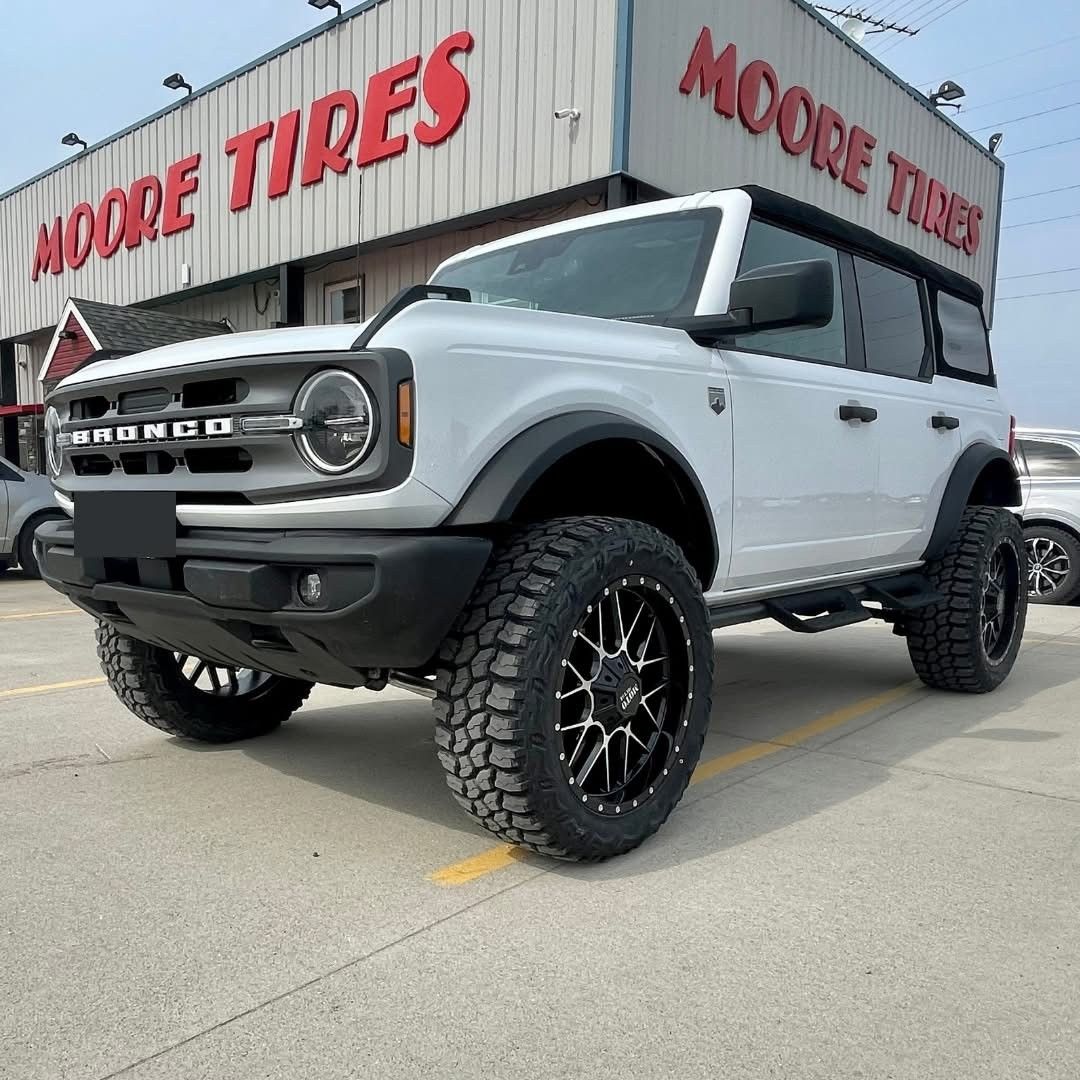 White Ford Bronco SUV with black wheels in front of 