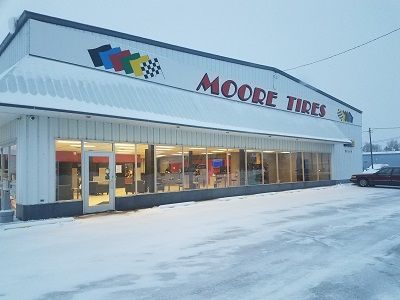 Moore Tires store in a snowy setting. Signage and colorful logos.