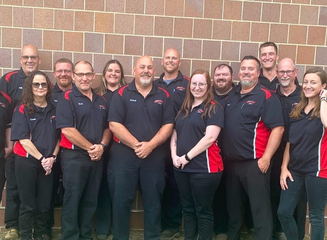 Group of people in matching shirts posing in front of a brick wall.