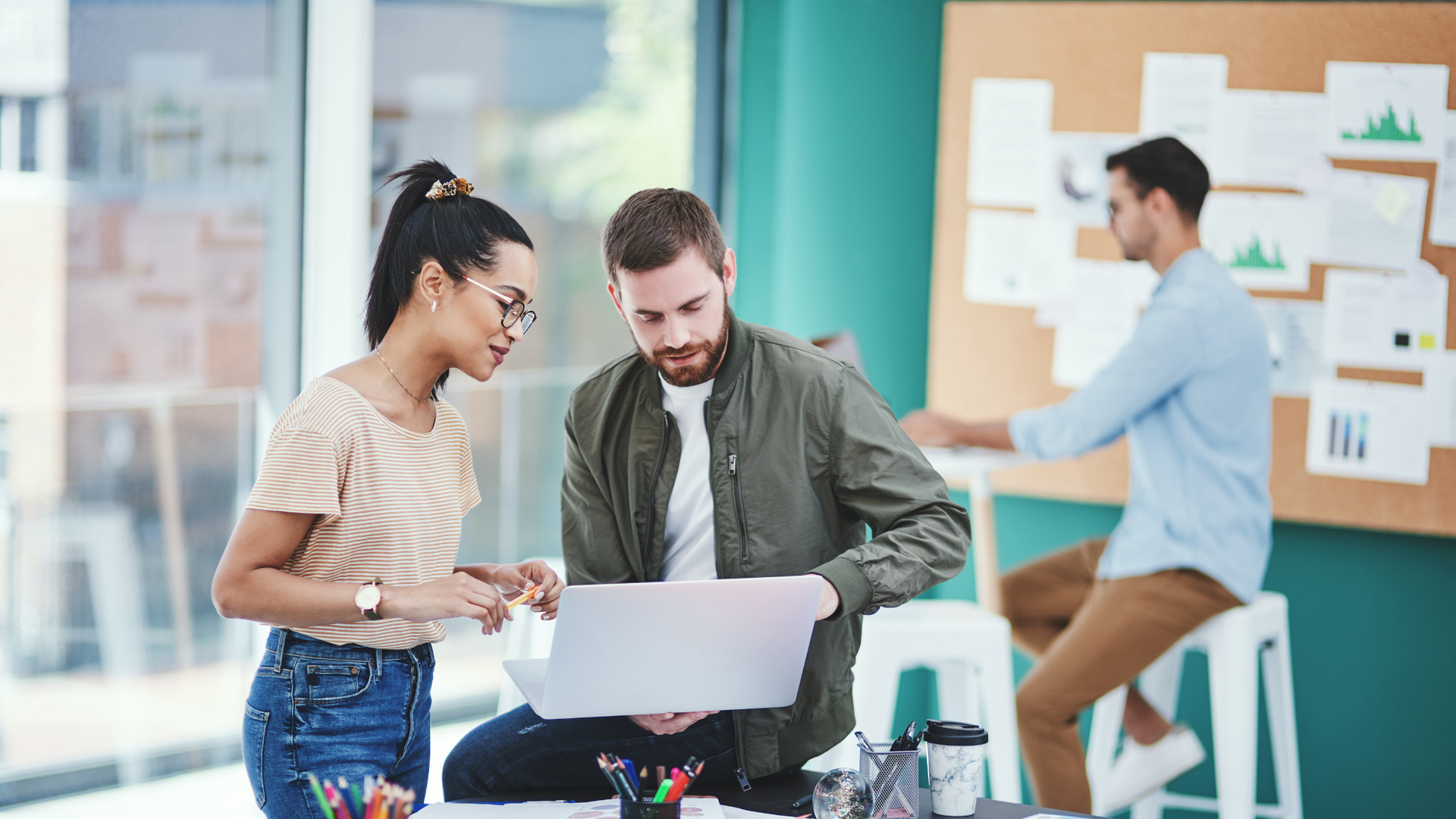 A man and a woman are looking at a piece of paper in an office.