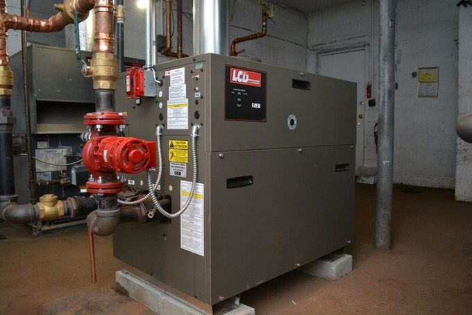 A water heater inside a wooden cabinet, against a textured brick wall with blue squares.