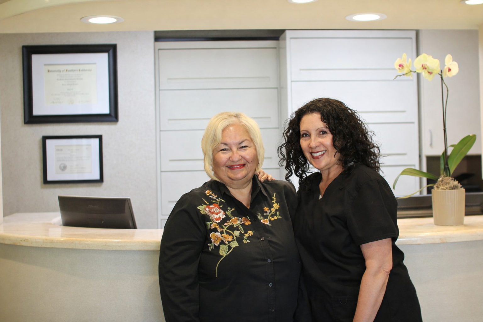 Three women are posing for a picture in a dental office.