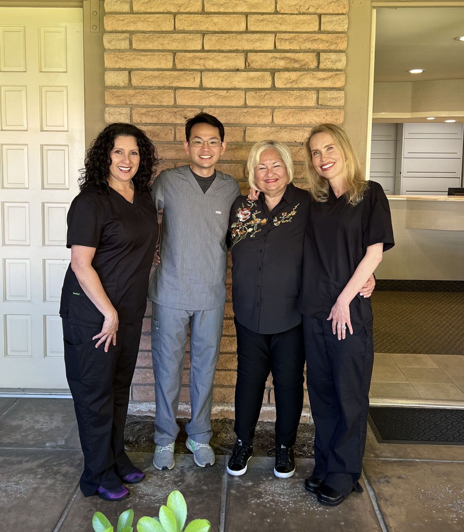 A group of people posing for a picture in front of a brick wall