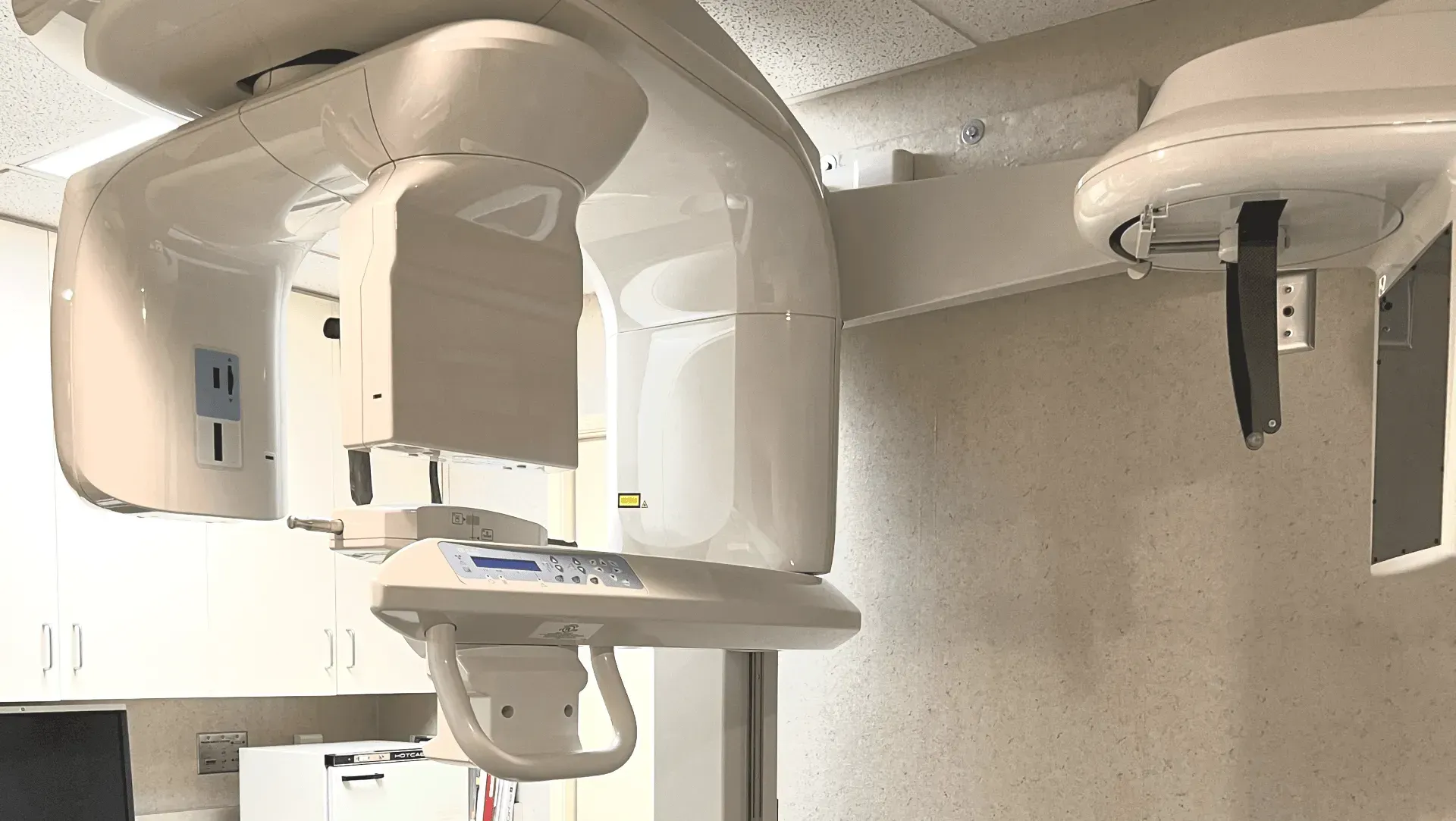 A dental office with a dental x-ray machine hanging from the ceiling.