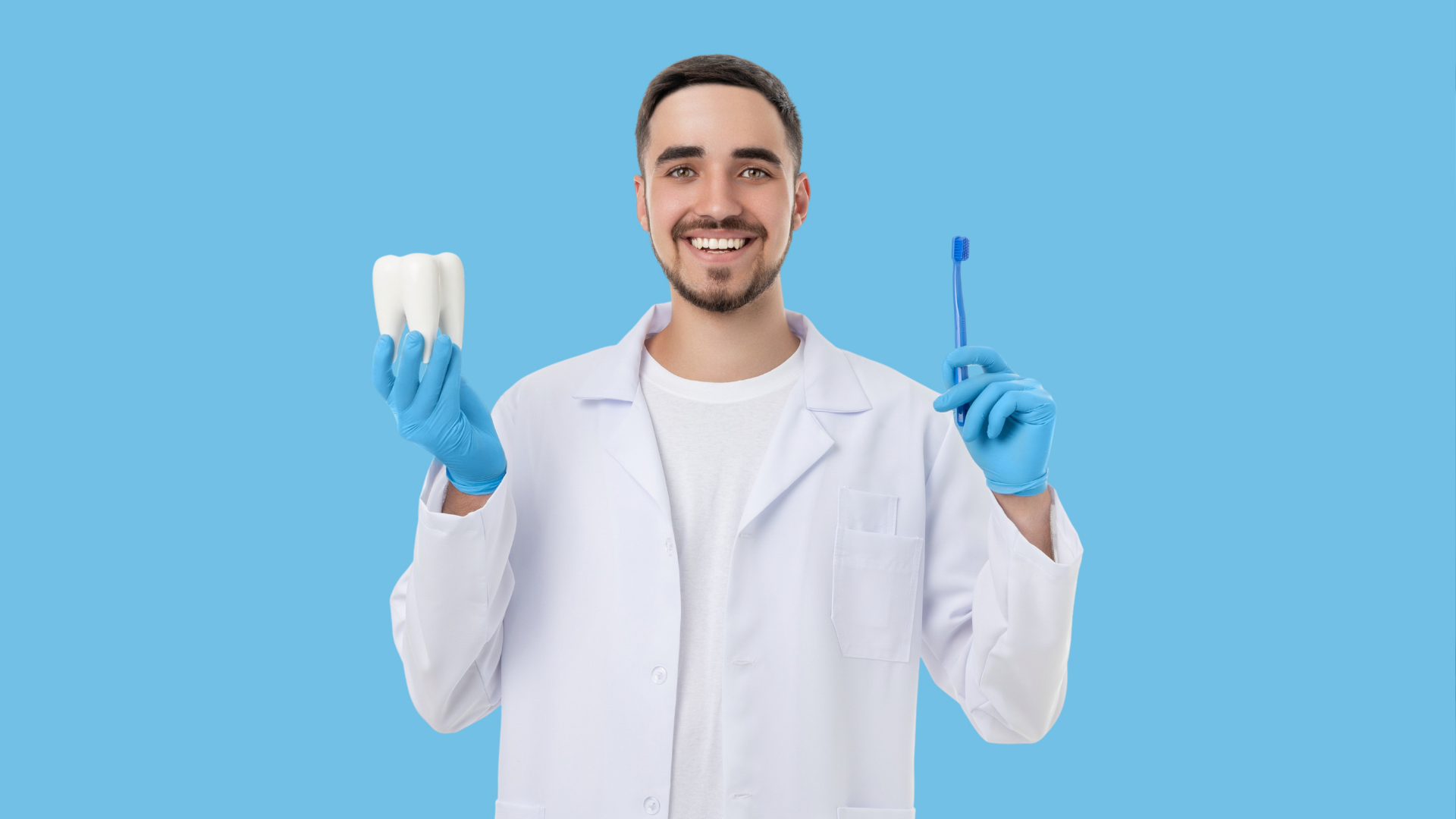 Dentist in white coat holding a dental mold and toothbrush, smiling against a blue background