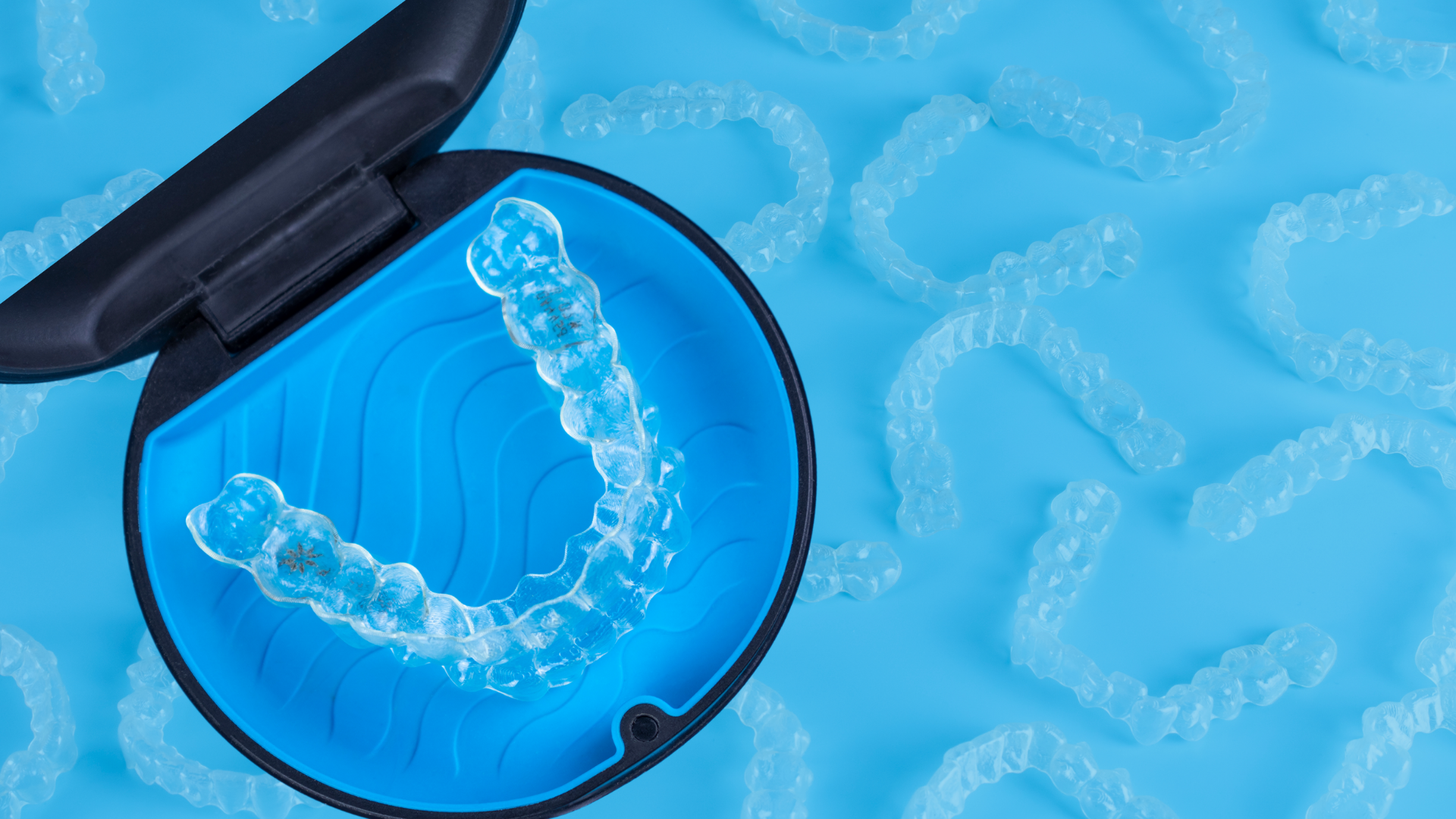 A pair of invisalign aligners in a case on a blue surface.