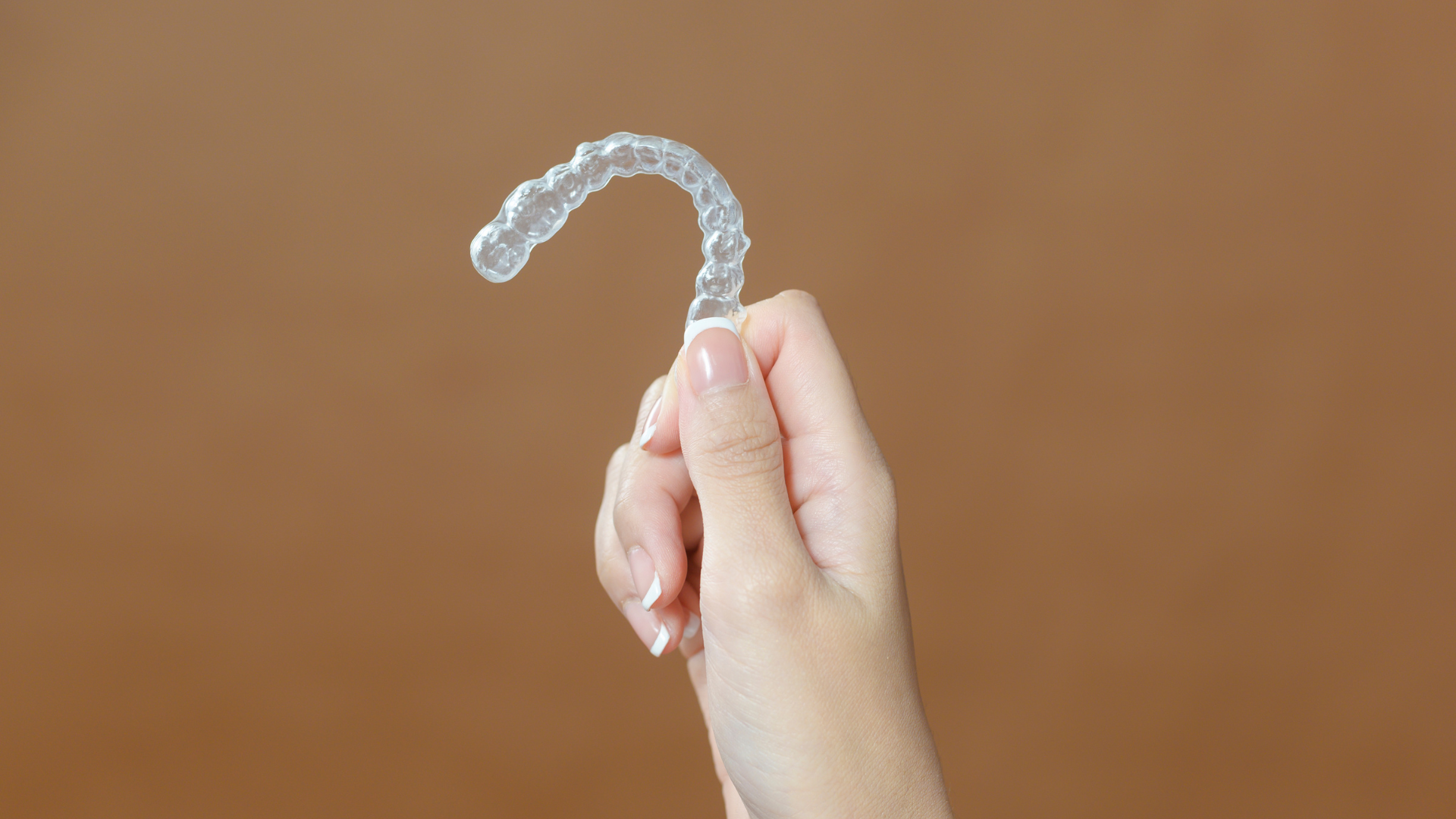 A woman is holding a clear brace in her hand.