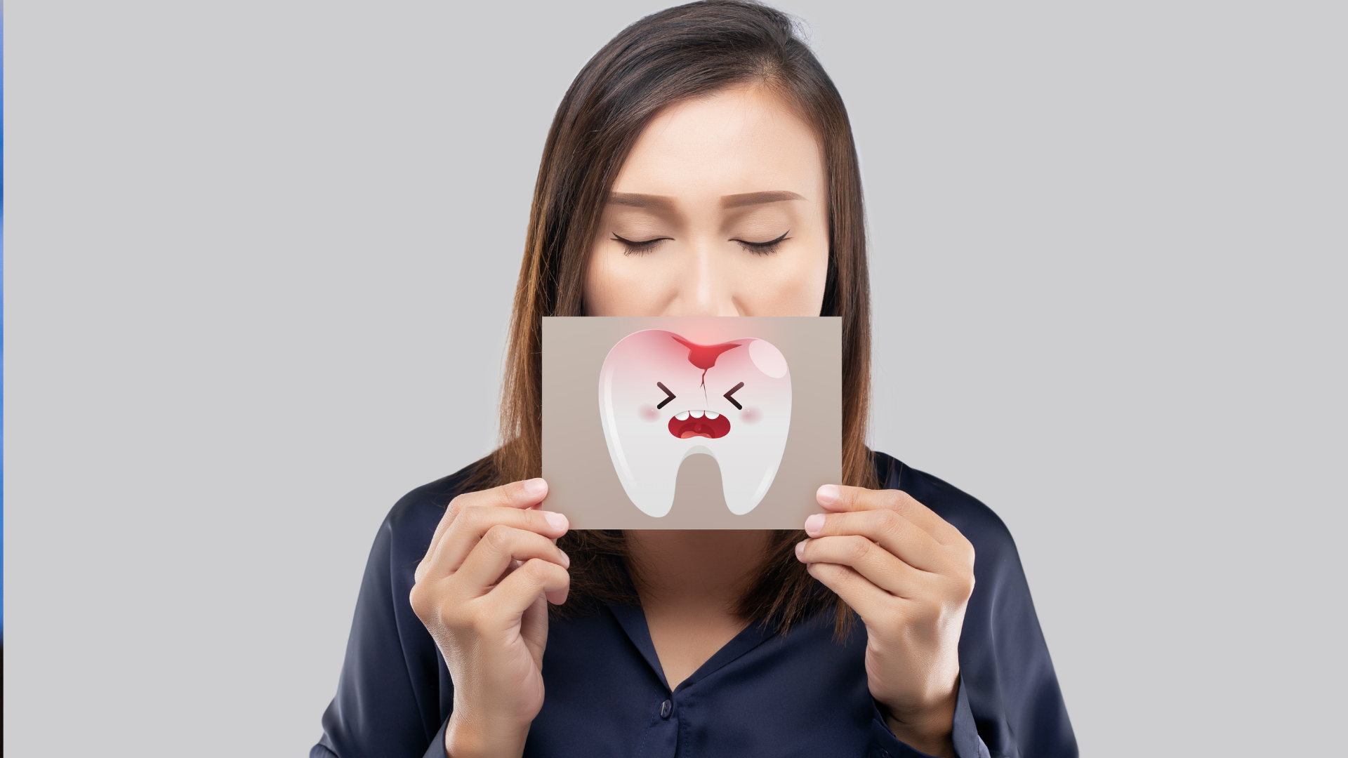 A woman is holding a card with a tooth on it in front of her face.