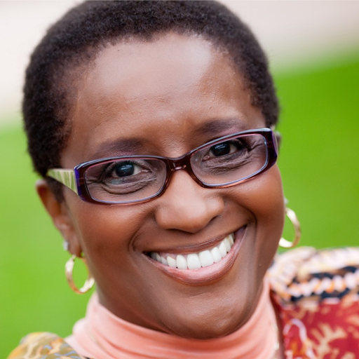 A woman wearing glasses and earrings smiles for the camera