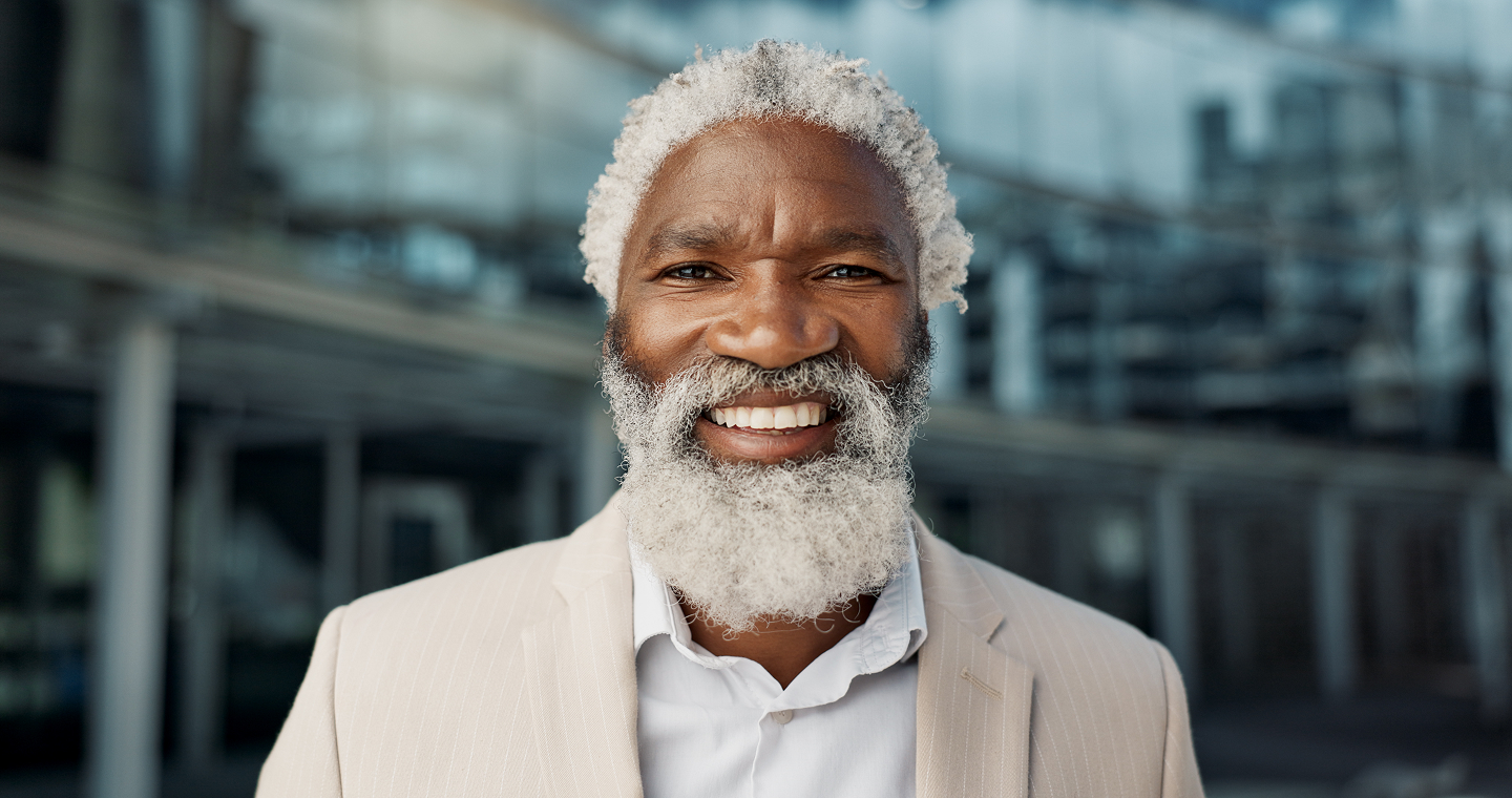 An older man with a gray beard is smiling for the camera.
