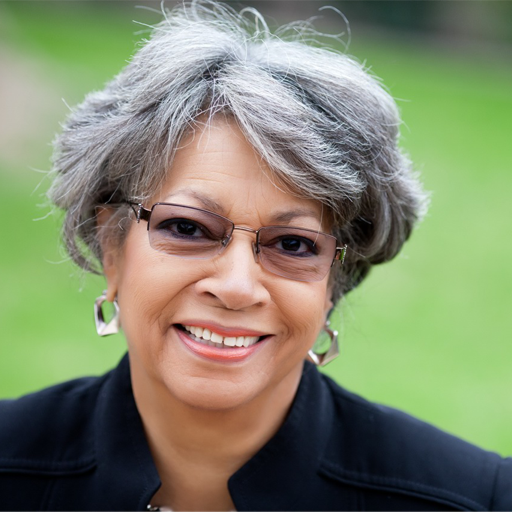 A woman wearing glasses and earrings is smiling for the camera