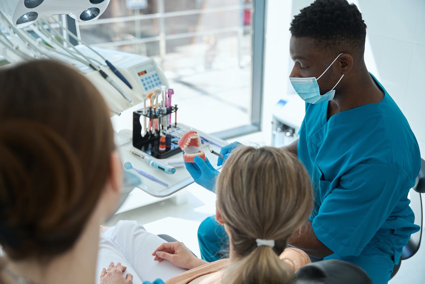 A dentist is examining a patient 's teeth in a dental office.