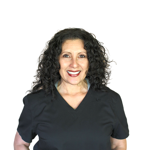 A woman with curly hair is wearing a black scrub top and smiling.