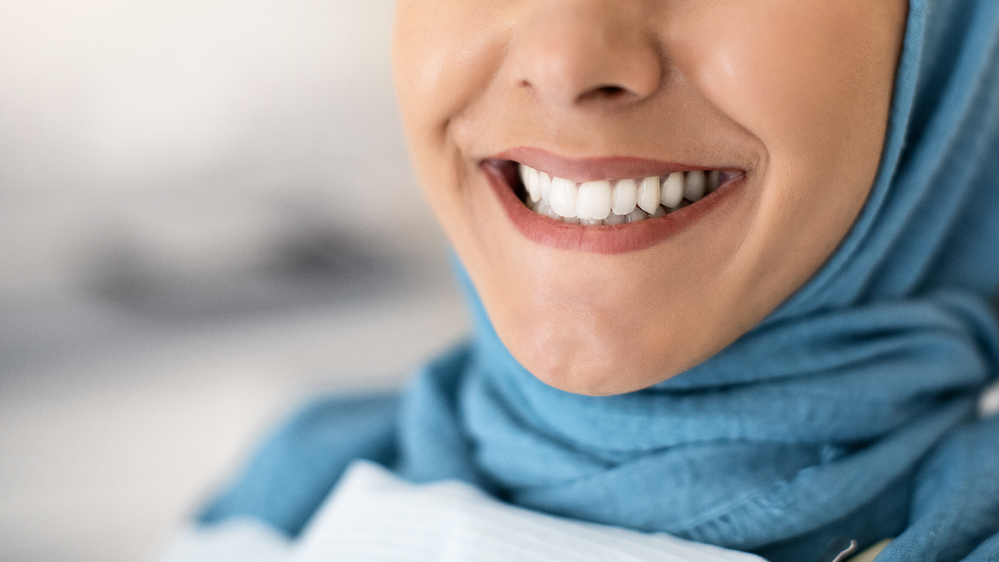 A close up of a woman wearing a hijab and smiling.