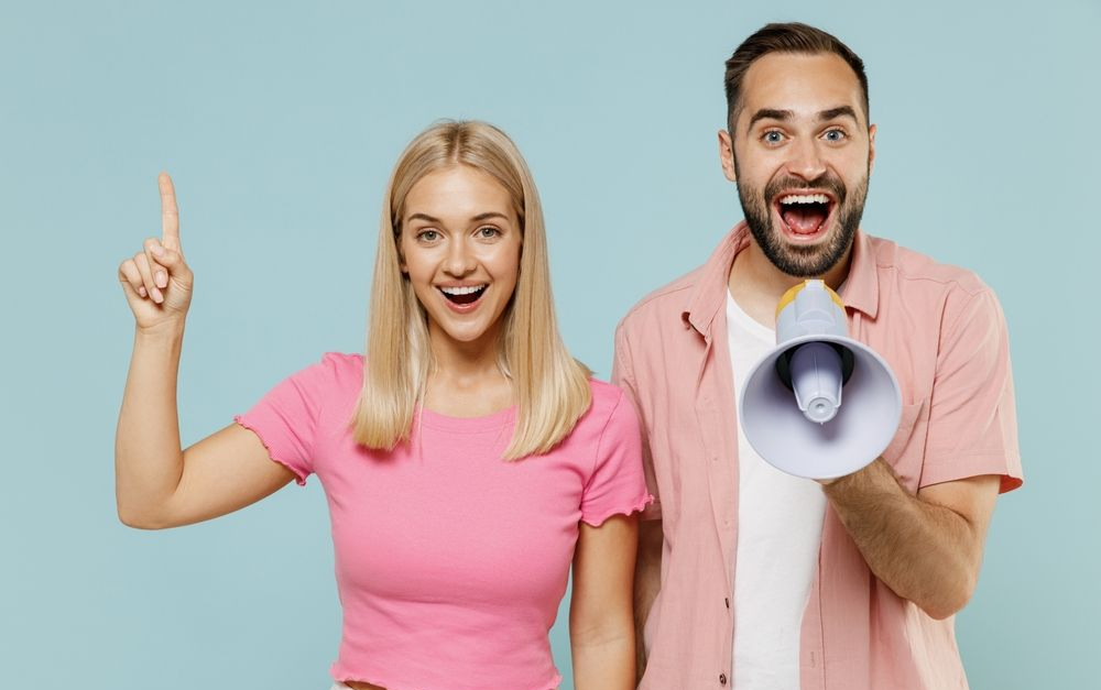 A man and a woman are standing next to each other holding a megaphone.