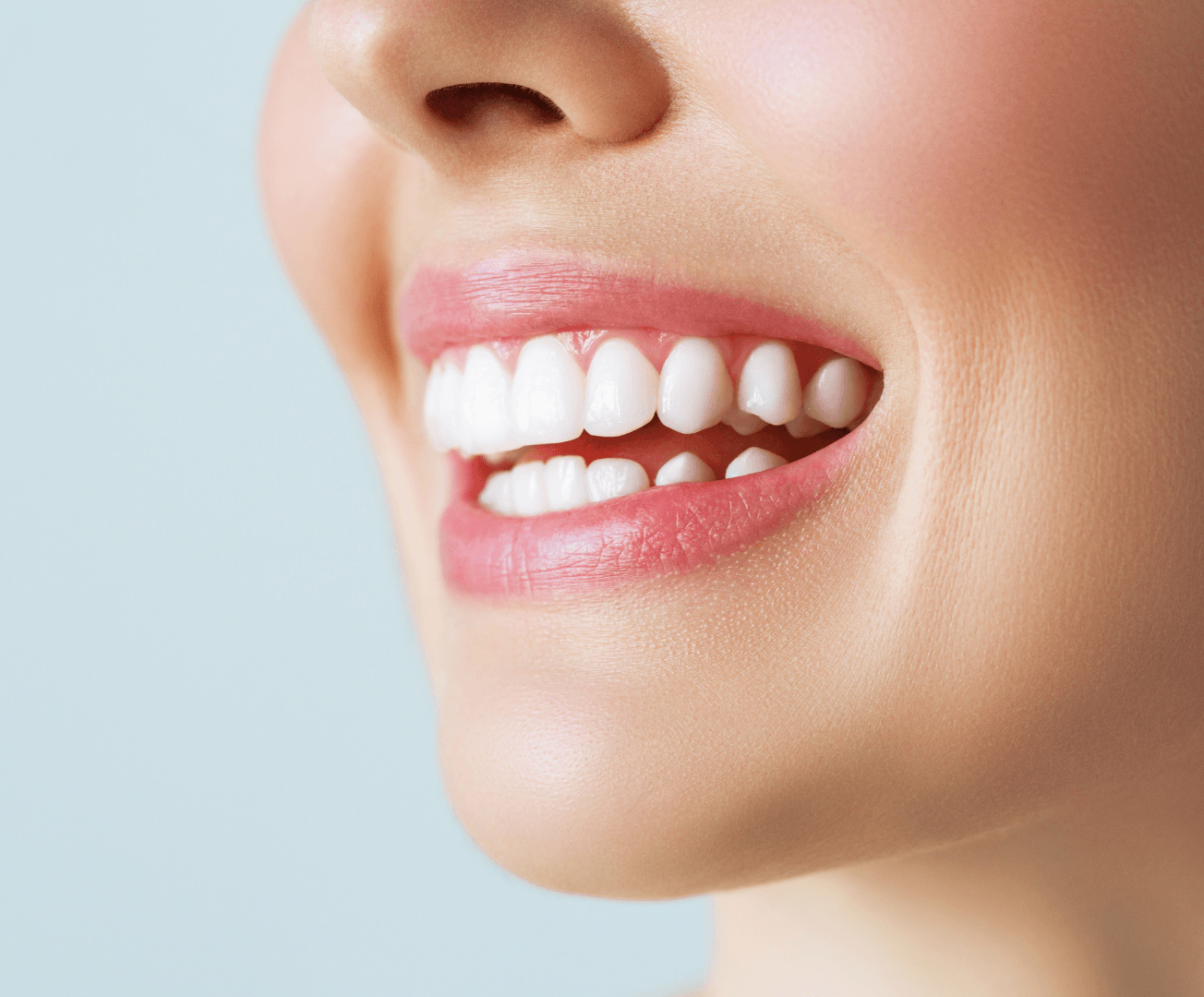 A close up of a woman 's smile with white teeth and pink lips.