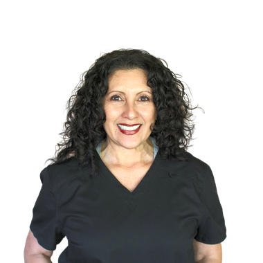 A woman with curly hair is wearing a black scrub top and smiling.