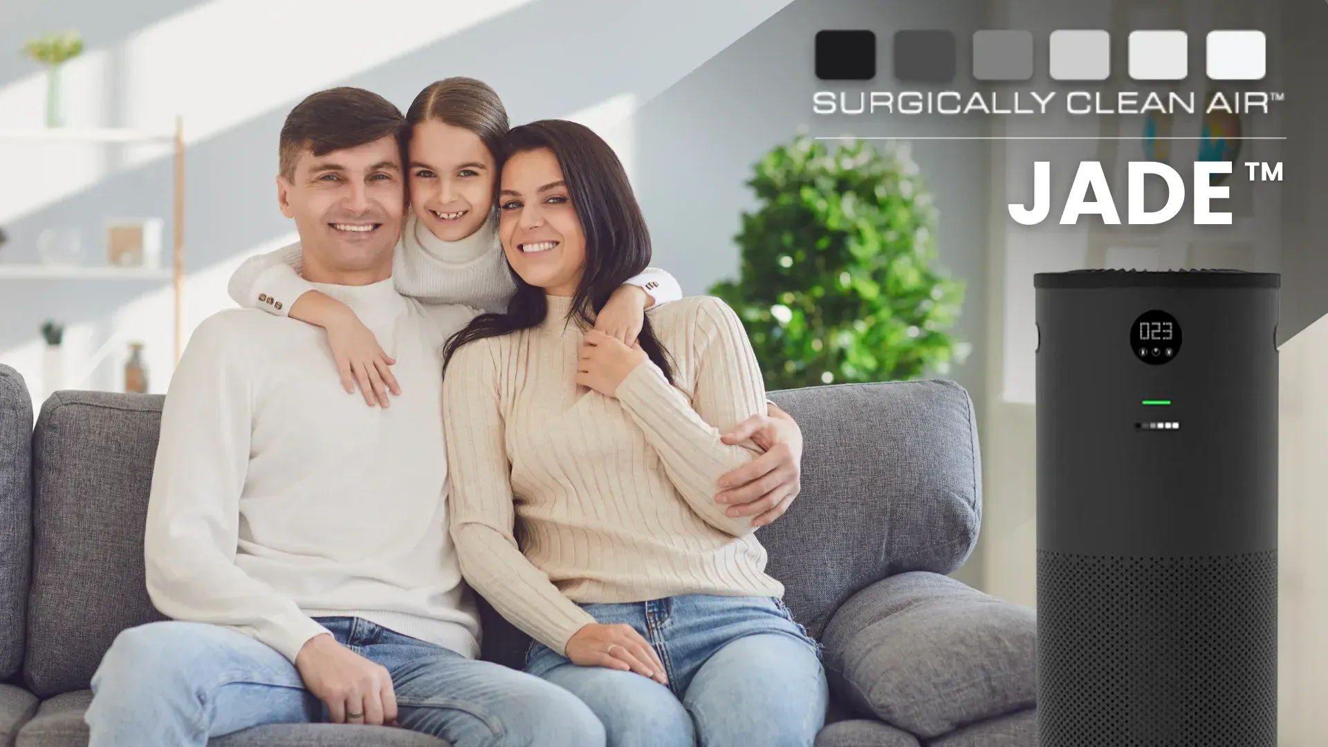 A family is sitting on a couch next to a jade air purifier.