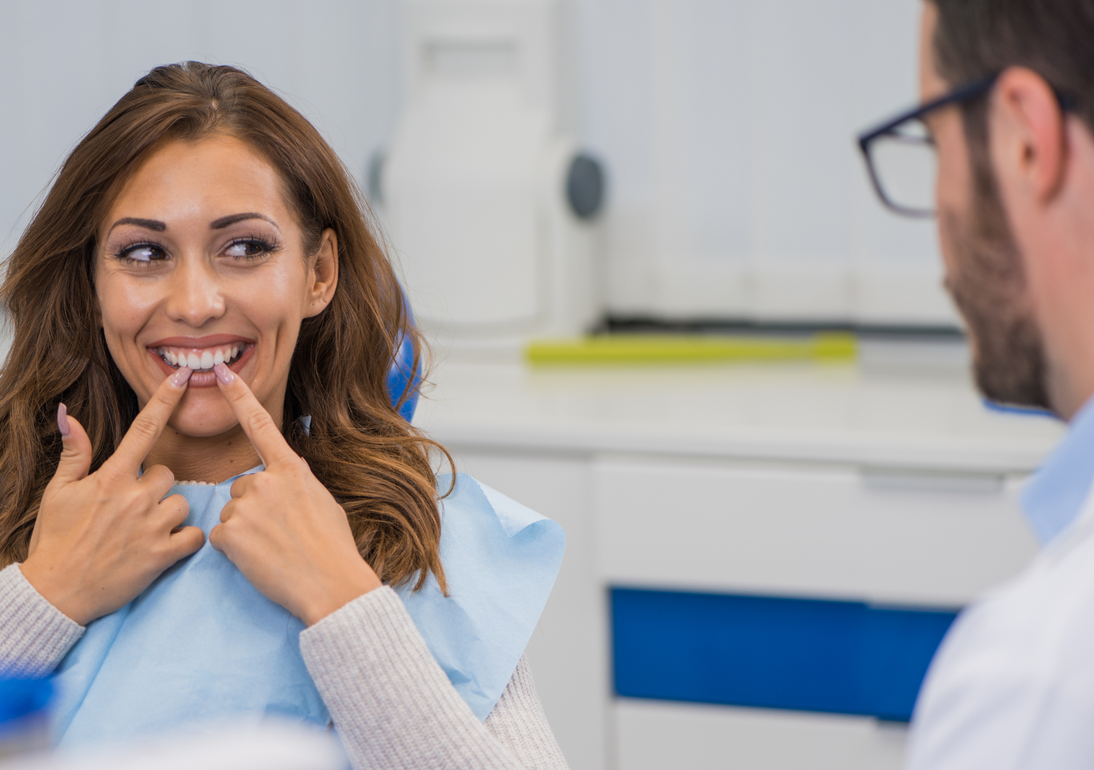 A woman is sitting in a dental chair talking to a dentist.