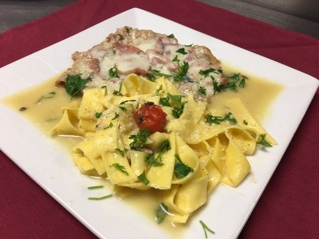 A white plate topped with pasta and meat on a red table cloth
