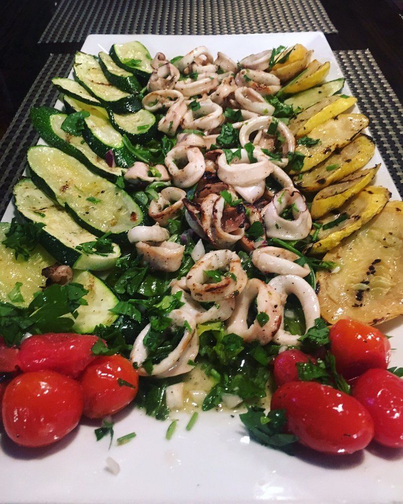 A white plate topped with vegetables and seafood on a table.