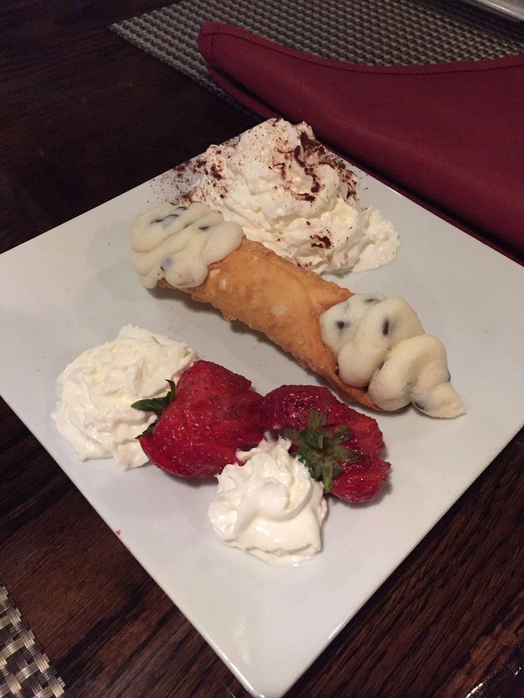 A dessert with whipped cream and strawberries on a white plate