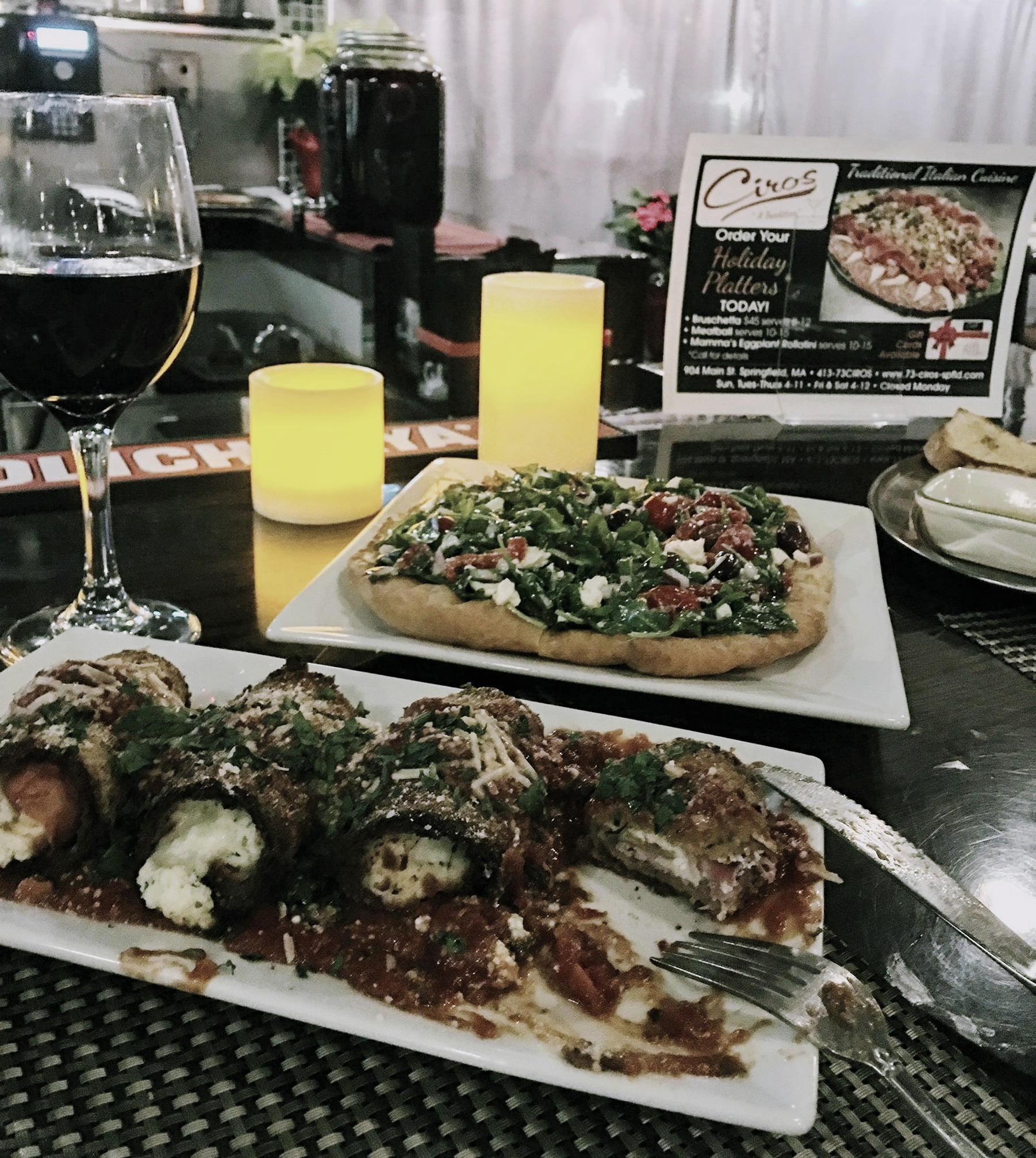A table with plates of food and a glass of wine