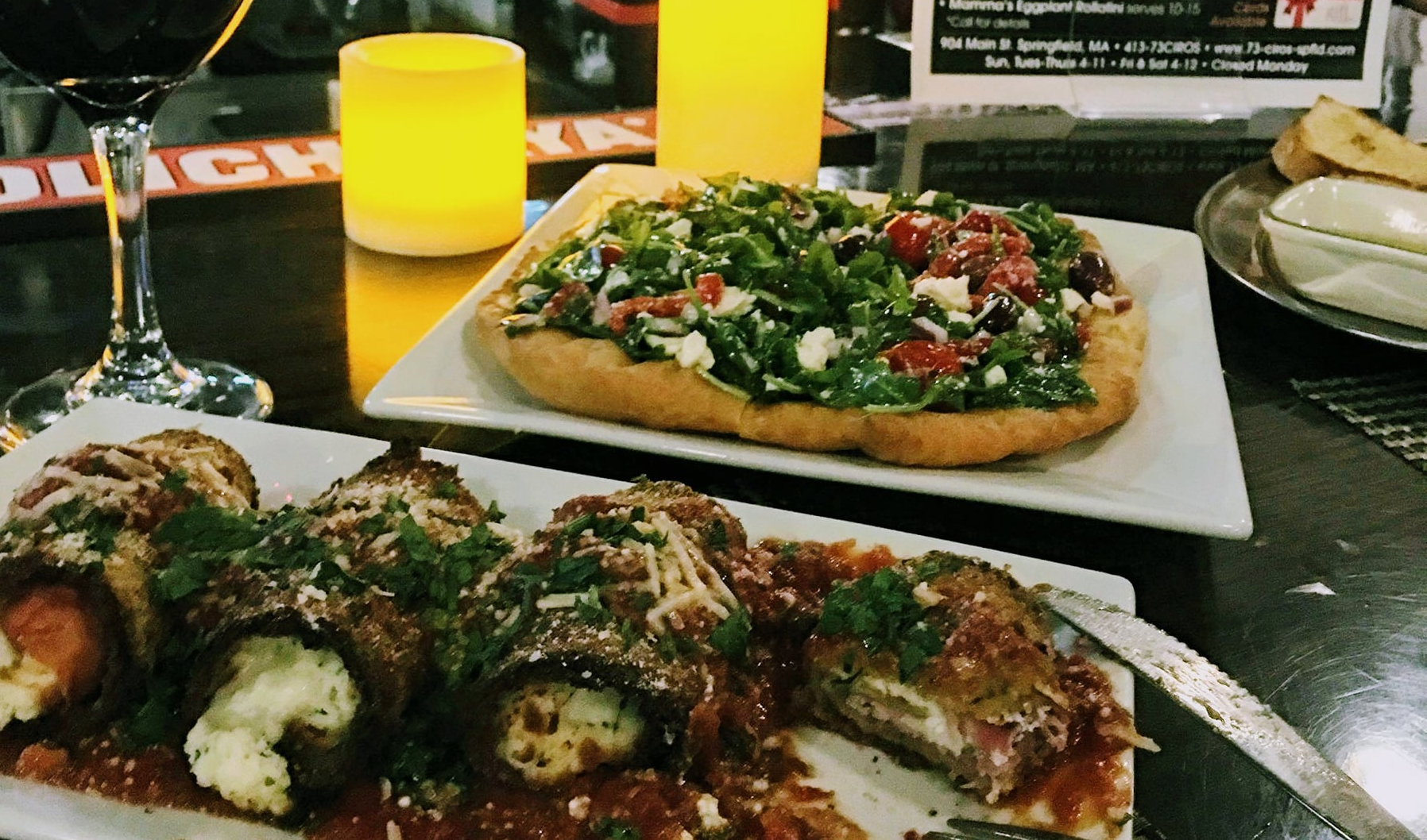 A table with plates of food and a glass of wine