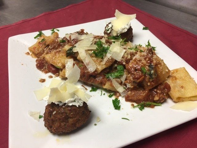 A white plate topped with pasta meatballs and cheese