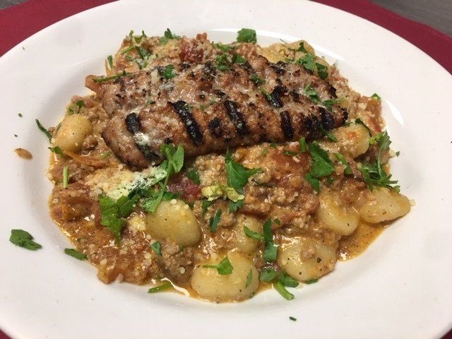 A plate of food with meat and gnocchi on a table.