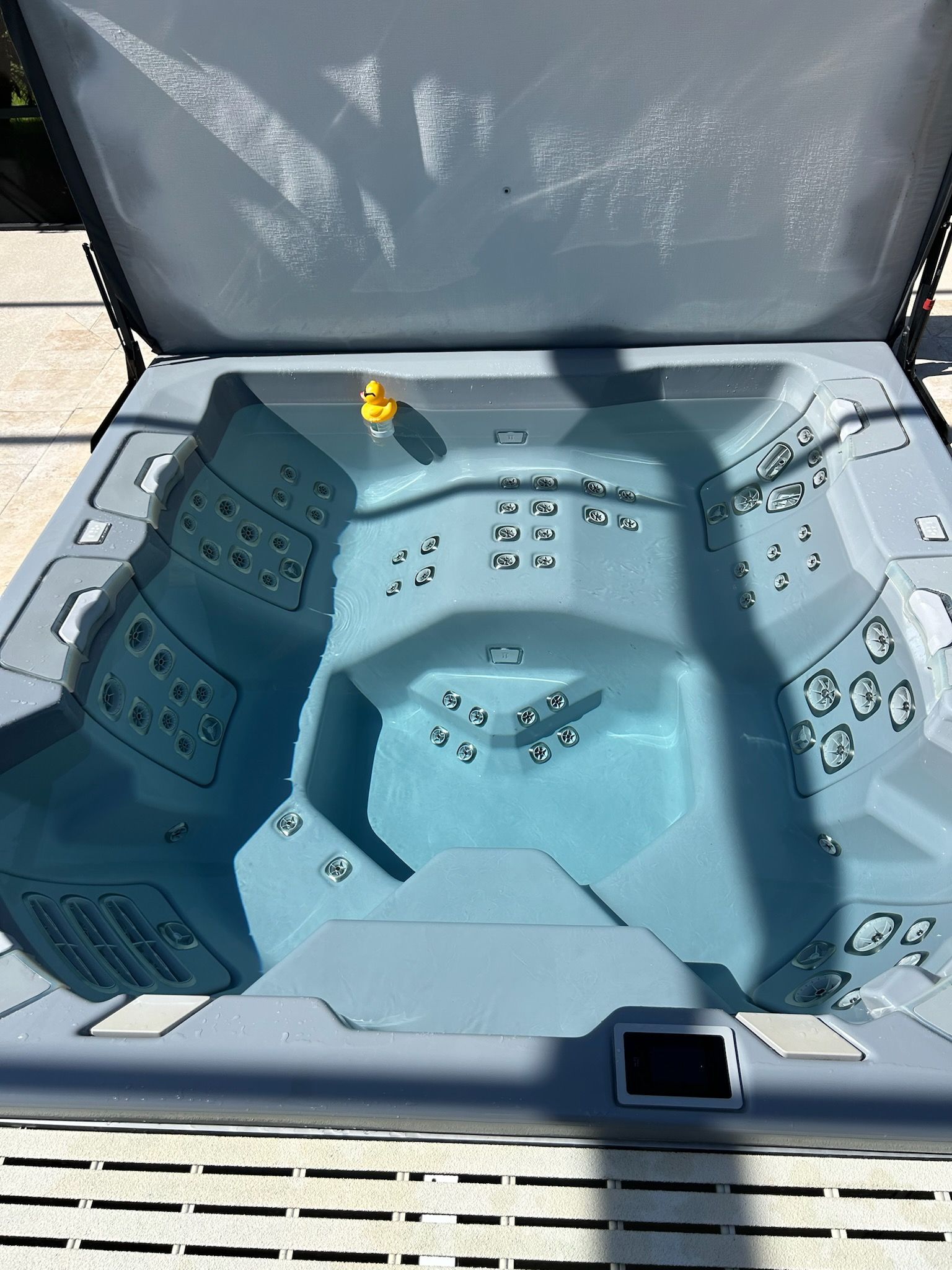 A hot tub with the lid open and a yellow rubber duck in it.