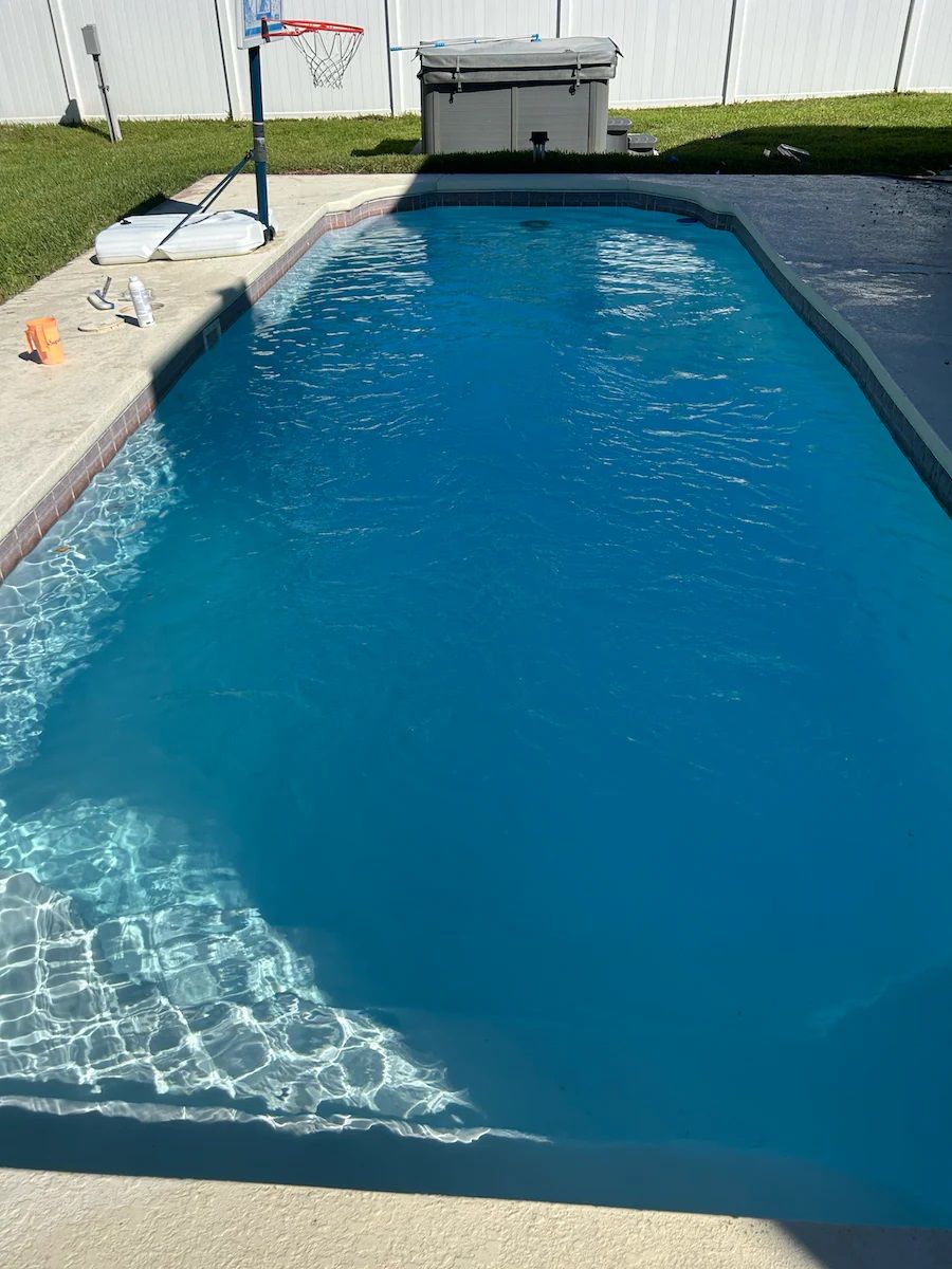 A large swimming pool with a basketball hoop in the background.