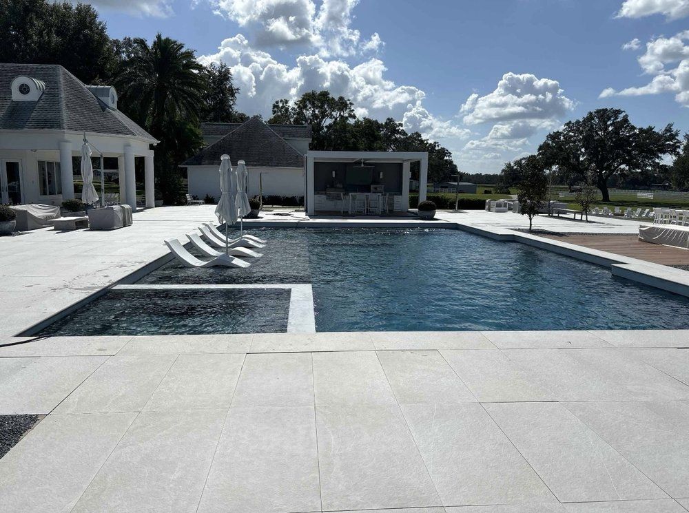 A large swimming pool is surrounded by chairs and umbrellas