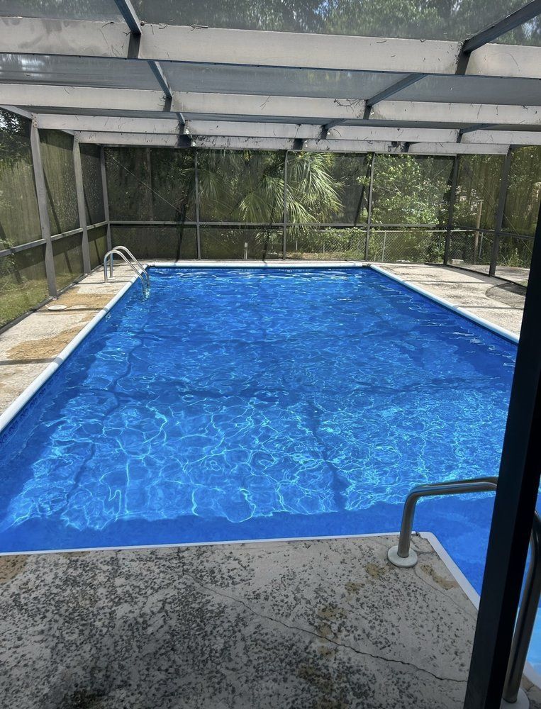 A large swimming pool is under a screened in area.