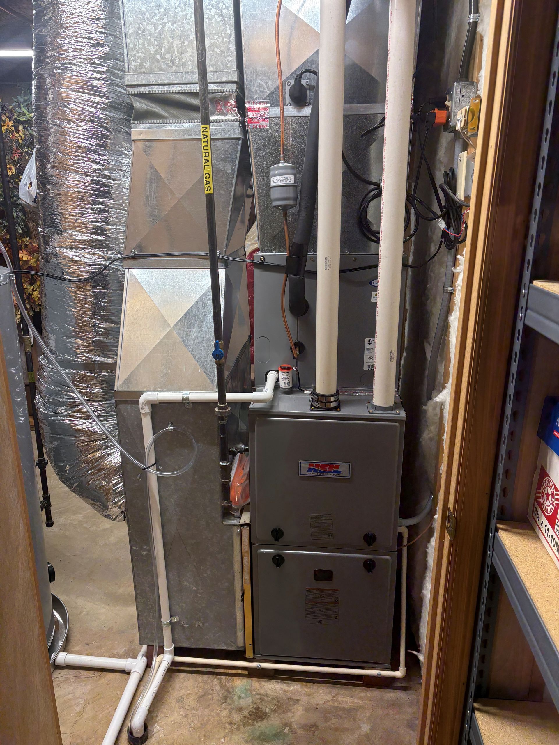 Person in overalls repairs ceiling air conditioning unit.