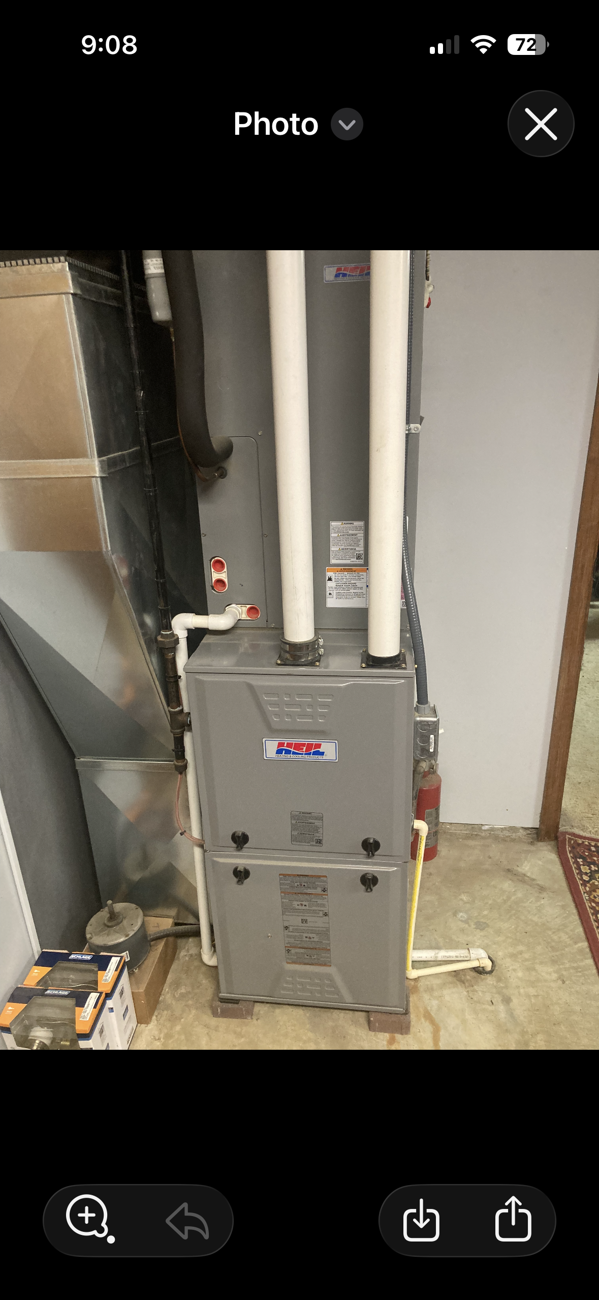 Hand adjusting a thermostat on a white wall near a window.