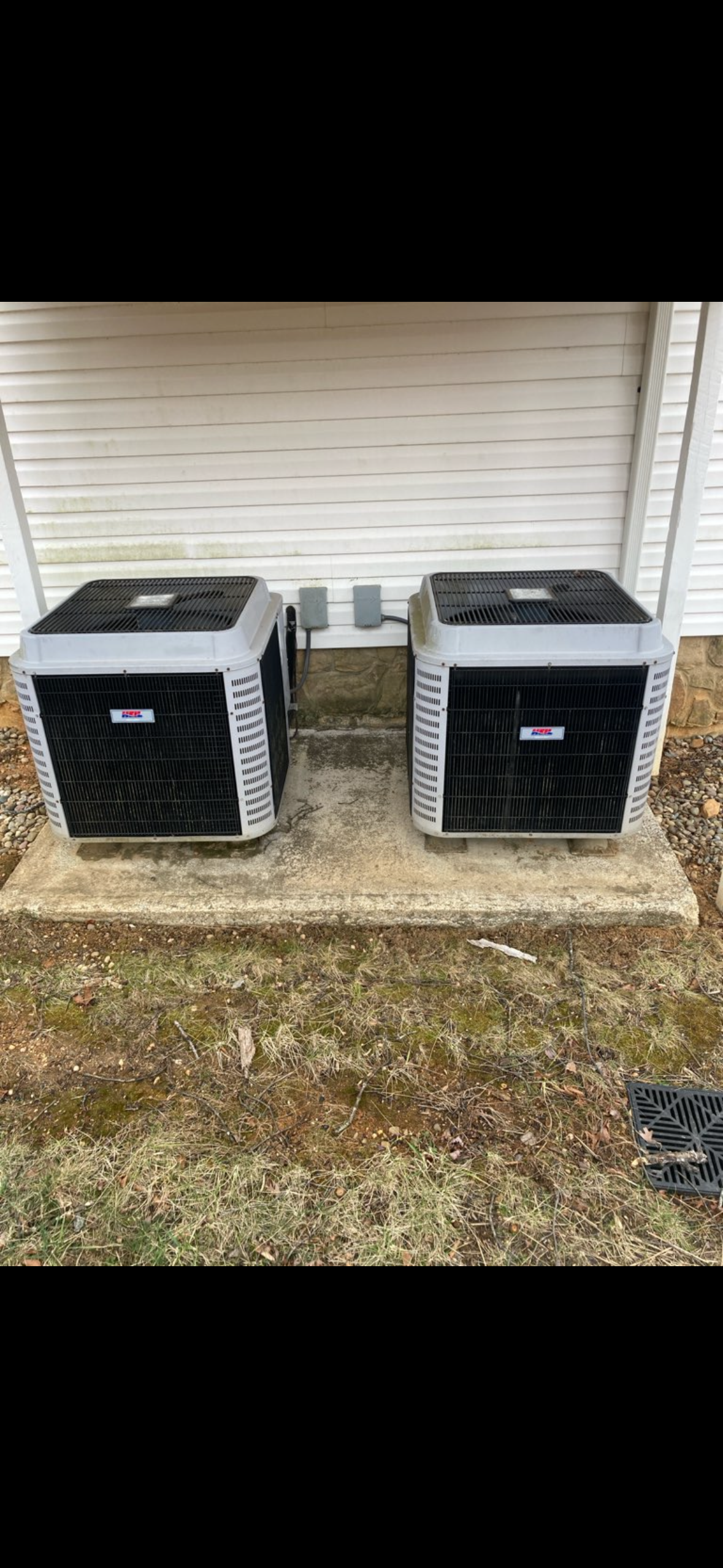 Person servicing an air conditioning unit outside a brick building.