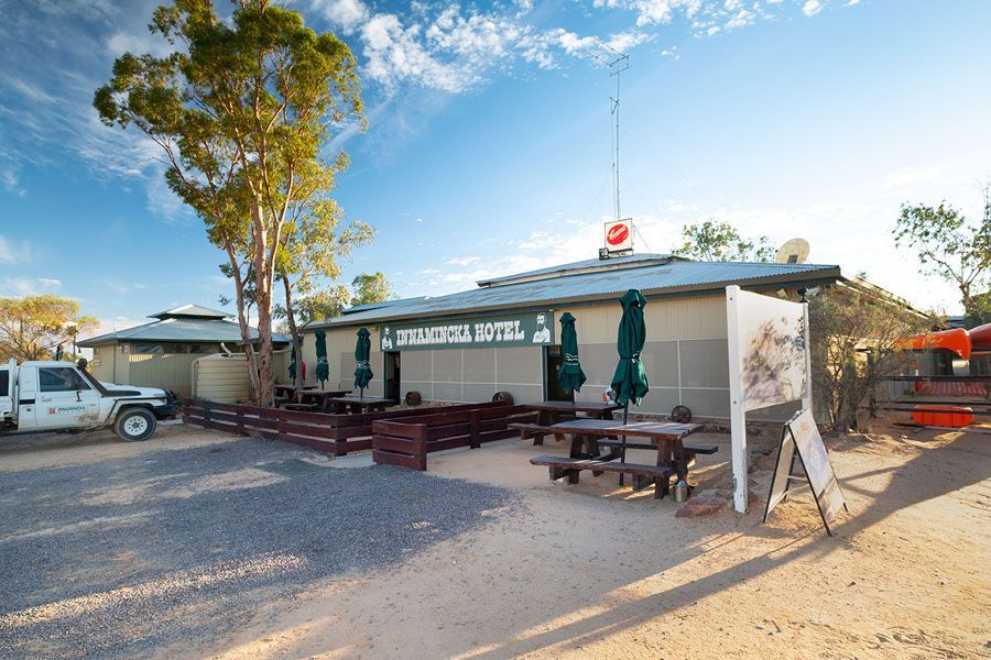 Outback hotel with outdoor seating and a truck parked outside on a sunny day.
