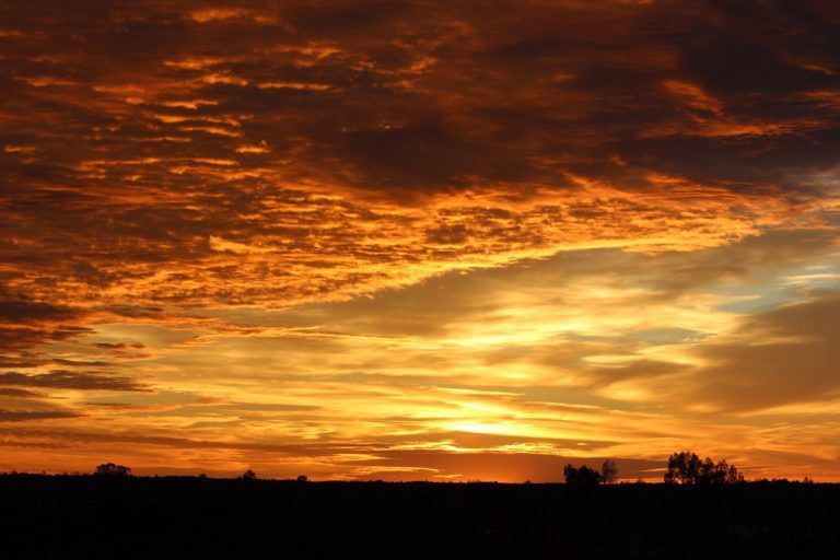Fiery sunset with orange, yellow, and dark clouds over a dark horizon.