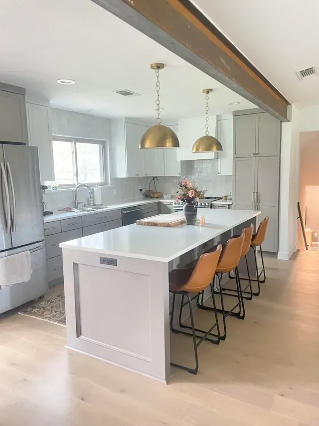 Modern kitchen with gray cabinets, white countertops, and gold pendant lights.