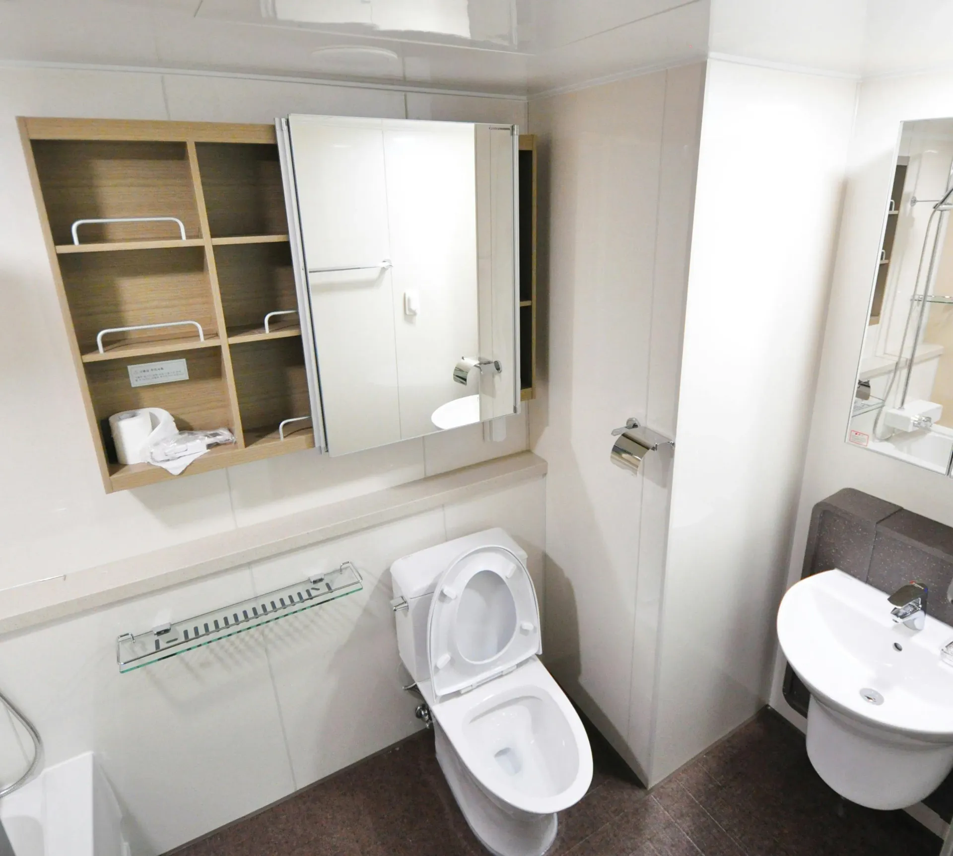 Small bathroom with a toilet, sink, and medicine cabinet; white walls.