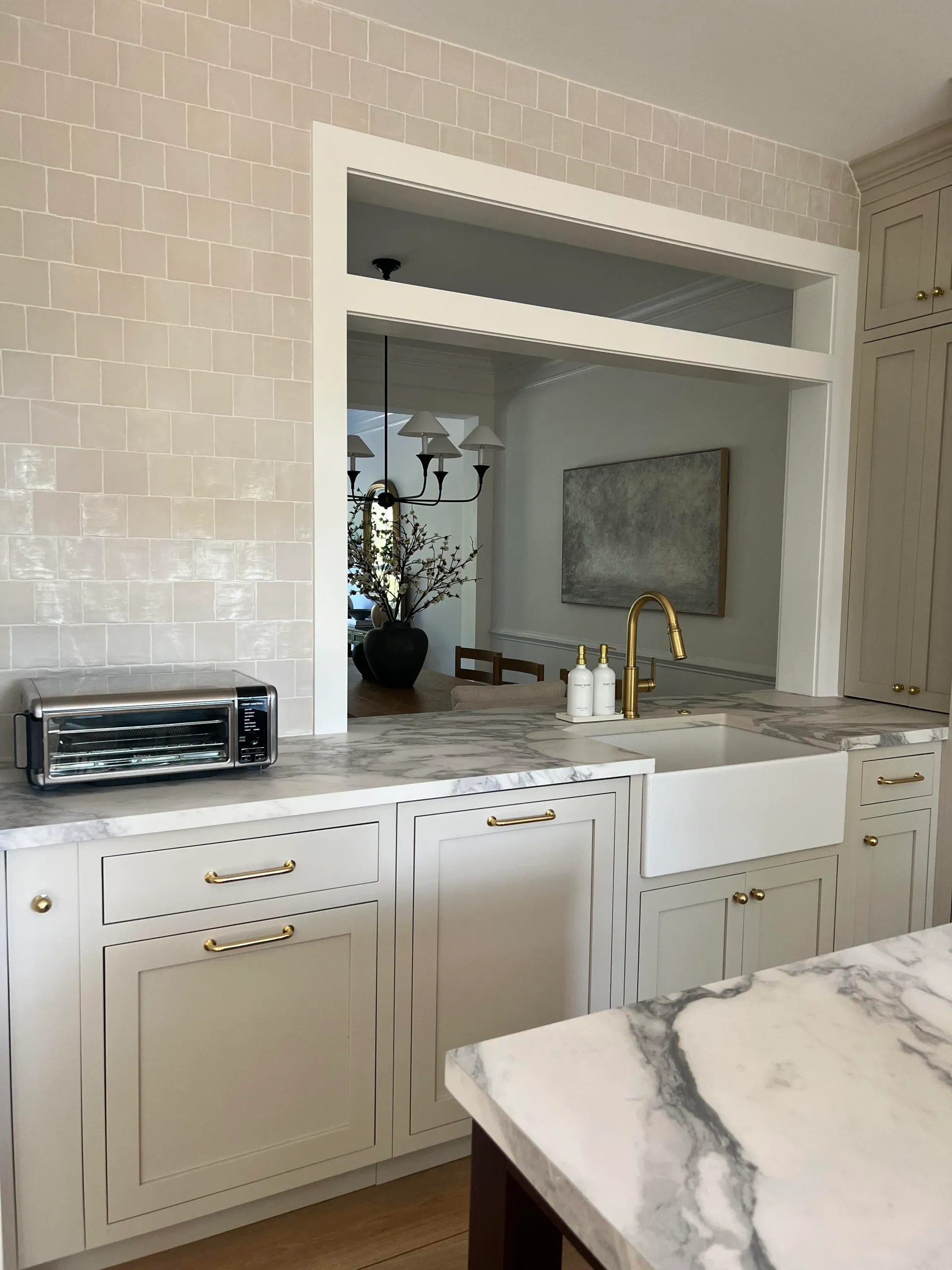 Kitchen with white cabinets, marble countertops, and a pass-through to a dining area.