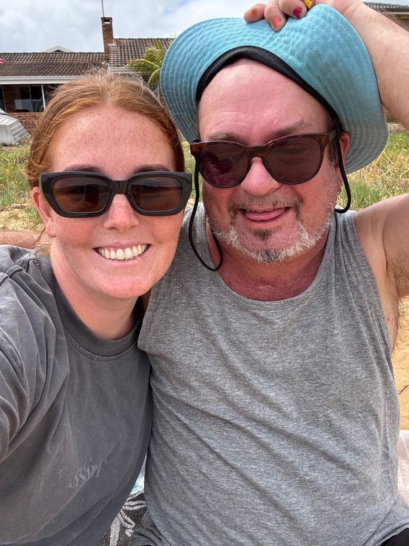 Woman giving scalp massage to another woman, indoors. One has pink hair.
