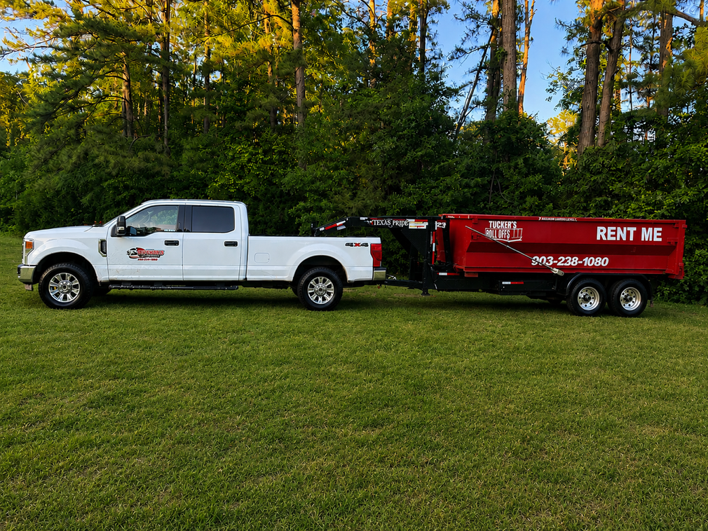 Red dump trailer with raised bed and black frame parked beside a corrugated metal building.